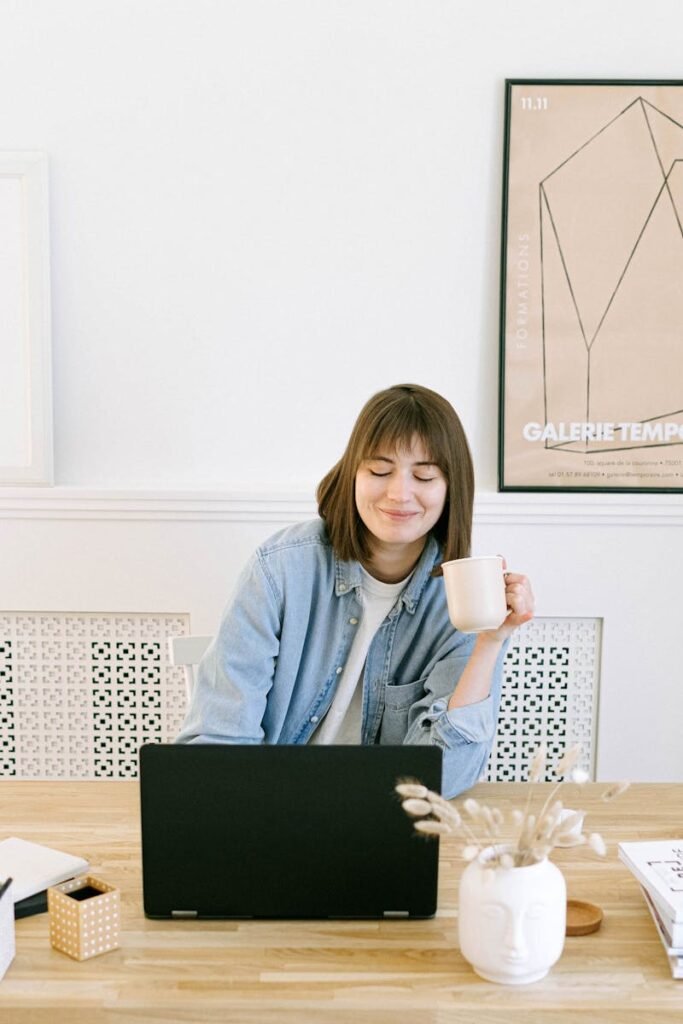 Woman Drinking Coffee and Looking at a Laptop