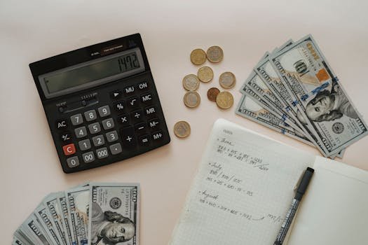 Passive income Black Calculator beside Coins and Notebook